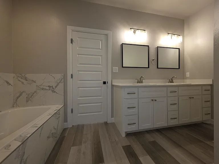 The Master/Primary bath features a soaking tub surrounded in marble tile & double vanity.