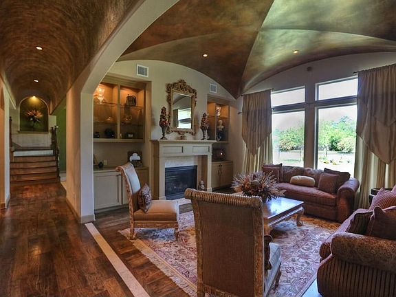 In the formal living room, seamless glass windows and custom silk drapes picture frame the backyard fountain view.