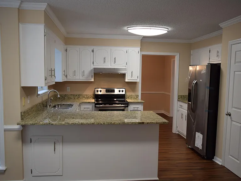Past the half bath, enter into the kitchen which has a beautiful grainite breakfast bar, stainless steel appliances and cabinet space