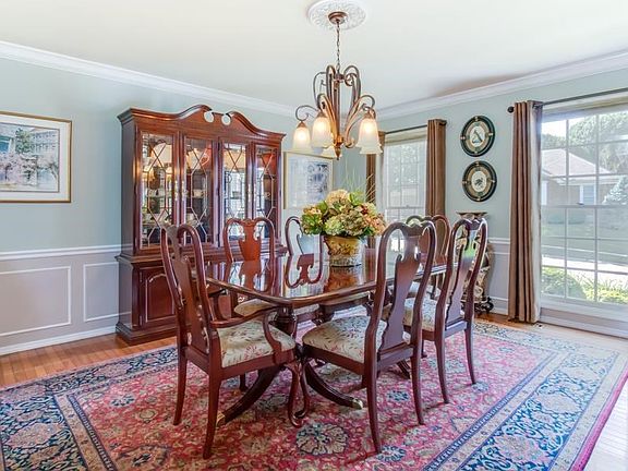 Large dining room with wainscoting and crown moulding.  Floor to ceiling windows.