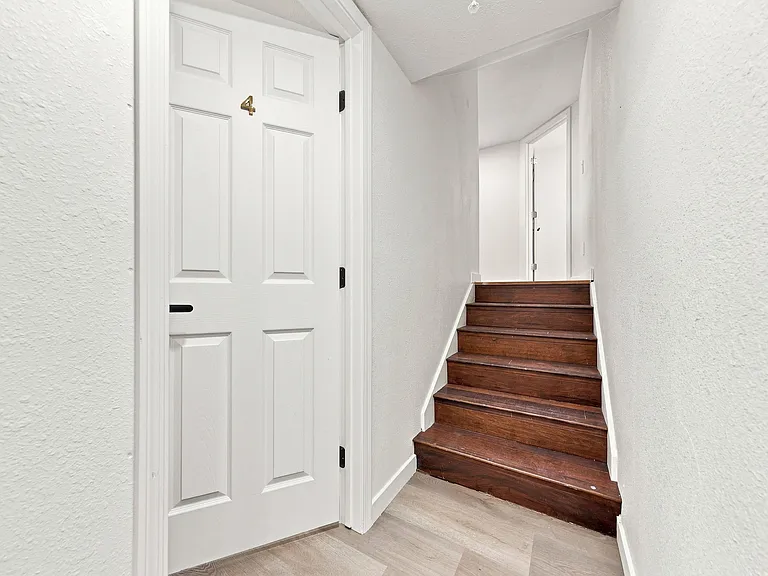 Clean interior stairwell with wood steps, neutral walls, and easy access to nearby rooms on the upper level.