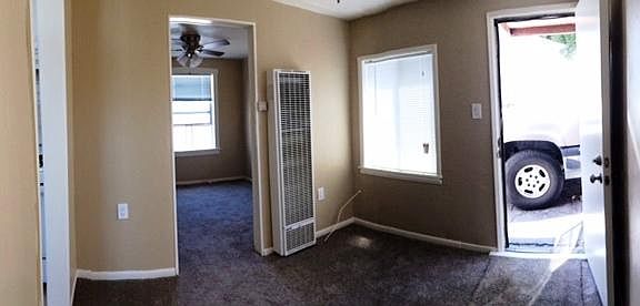 Part of the living room with front door on the right and bedroom door on the left