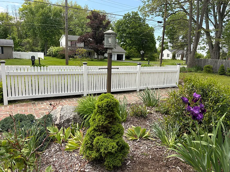From the front of the home looking towards the street, the landscaping offers beauty in every season with flowering plants and evergreens.