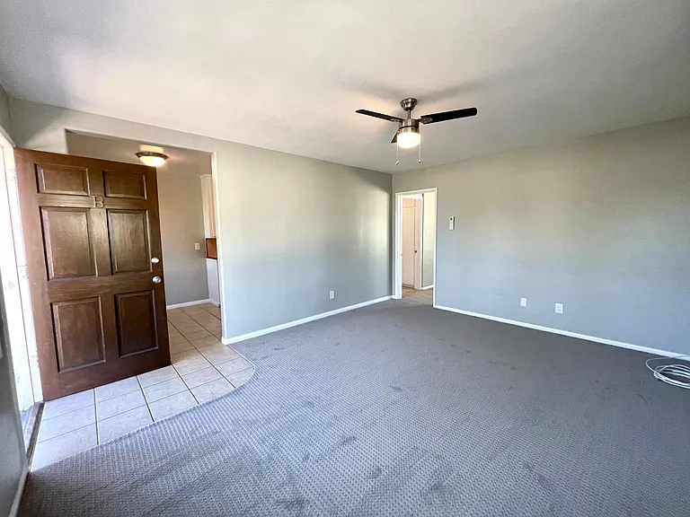 Living room looking towards entry and open eat-in kitchen. Bedroom door at the rear of the room.