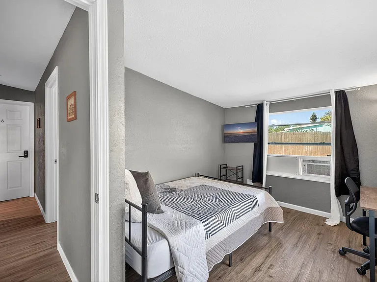 Room 4 featuring full-size bed, dedicated workspace, wall-mounted television, portable closet & private entrance.