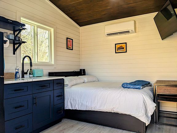 Full size bed with underbed storage, smart TV, and mini-split