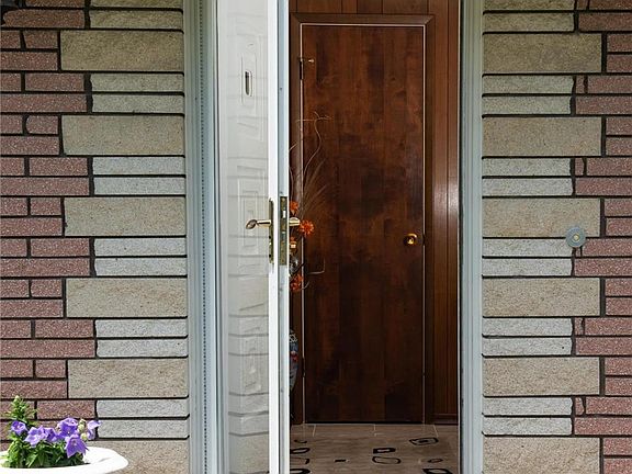 Beautiful stone detailing around the newer storm door that protects the vintage front door. The marble entry floor is shiny and 