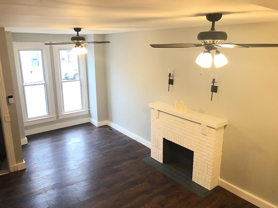 Spacious living room features decorative fireplace, ceiling fans, and 9' tall ceilings