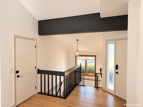 Welcoming entryway with white oak engineered hardwood flooring, black railing, and natural light. Virtually decluttered.