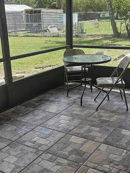 Screened-in patio with tiled flooring and a bistro table, offering a comfortable spot for outdoor dining and fresh air.