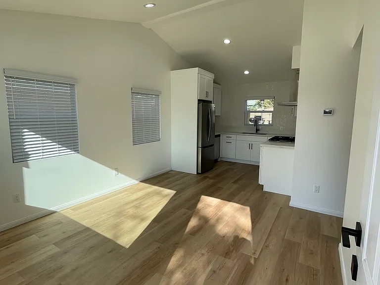 Bright, open living space with vaulted ceilings, natural light, and modern kitchen with stainless steel appliances.