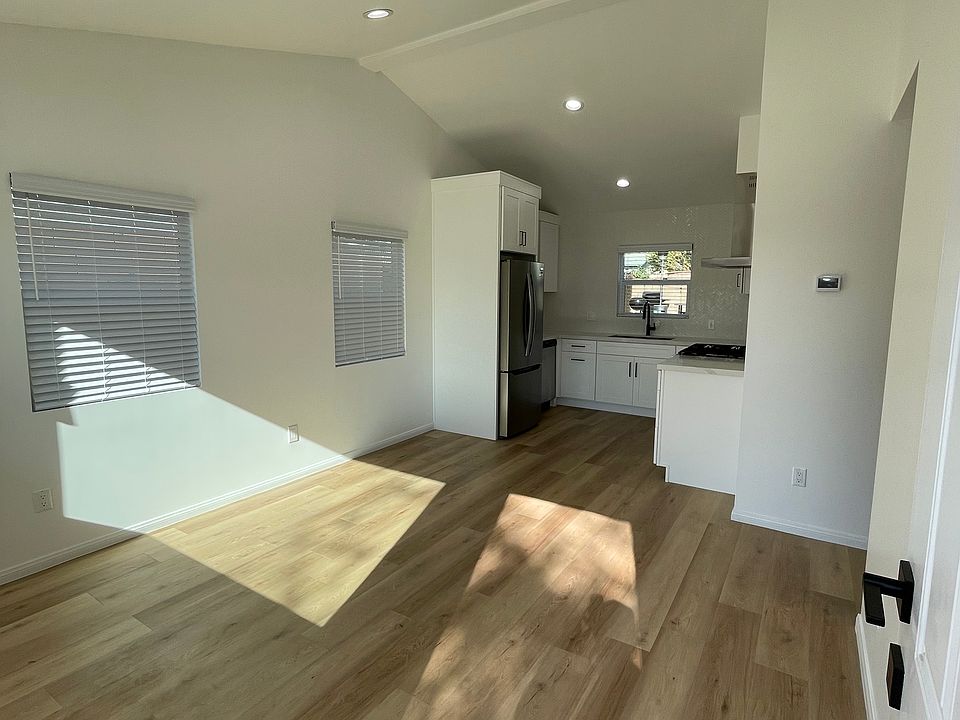 Bright, open living space with vaulted ceilings, natural light, and modern kitchen with stainless steel appliances.