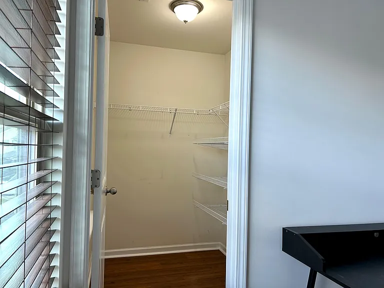 Walk-in closet with wire shelving and overhead light, offering convenient storage and easy organization.