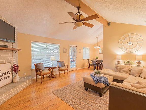 Living area with vaulted ceiling, hardwood floors, fan, and can lighting.