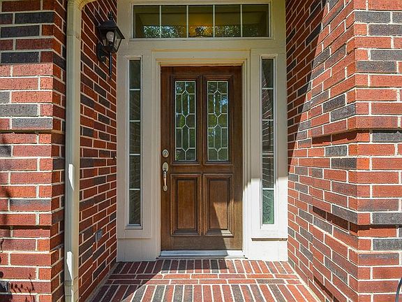 Welcoming covered brick entrance with a beautiful entry door with leaded glass detail and sidelights.
