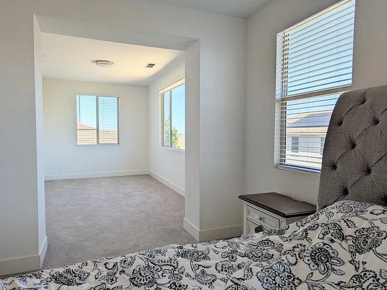 Enjoy floods of natural light in this spacious bedroom. Featuring expansive picture windows equipped with custom blinds and roller shade for privacy and style, this sun-filled retreat is a perfect sanctuary.