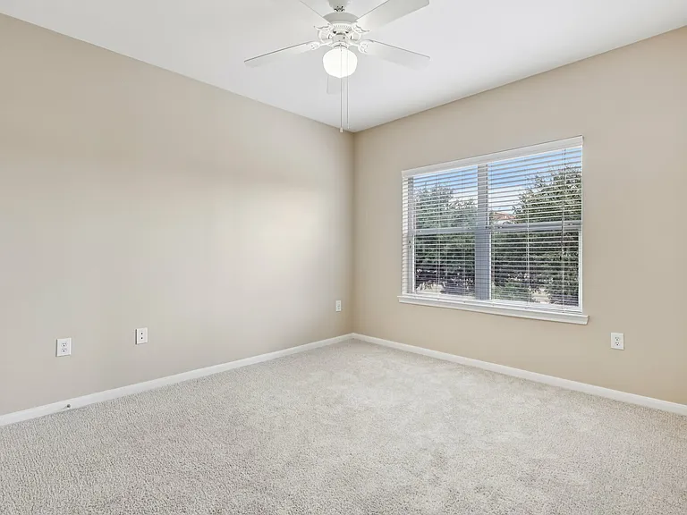 Bright and airy room with plush carpet, large window with garden view, and ceiling fan for comfort. Bright and airy room with plush carpet, large window with garden view, and ceiling fan for comfort.