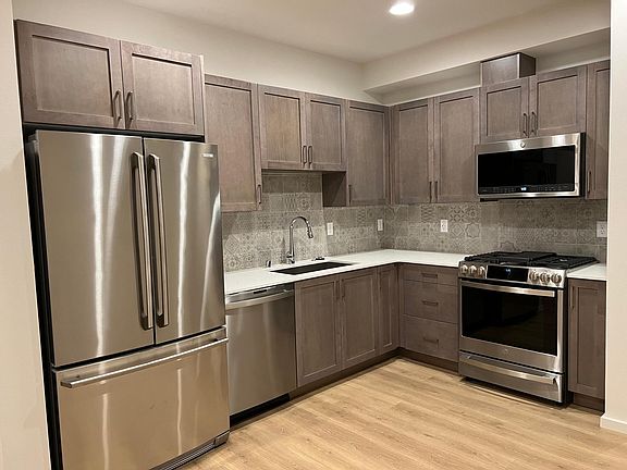Kitchen: 
Quartz countertops and stainless-steel appliances, including a gas range, microwave, refrigerator, and dishwasher
