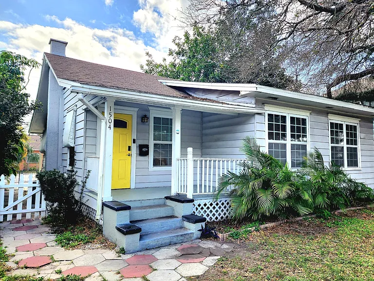Front of house with fully fenced in yard and porch