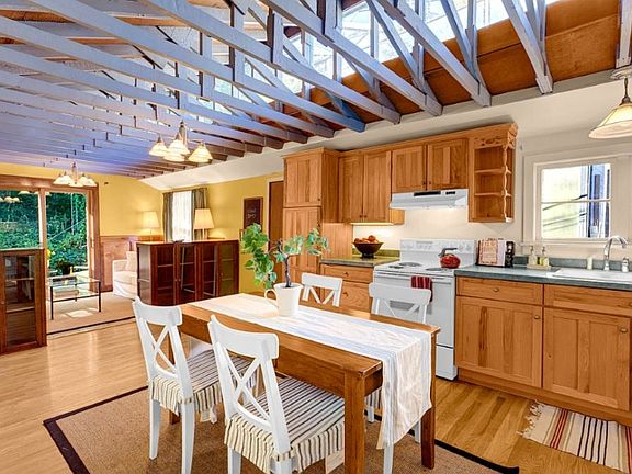 This large kitchen area w/ hardwood floors and custom maple cabinetry has views of the Aurora Bridge through skylit windows exposed trusses.