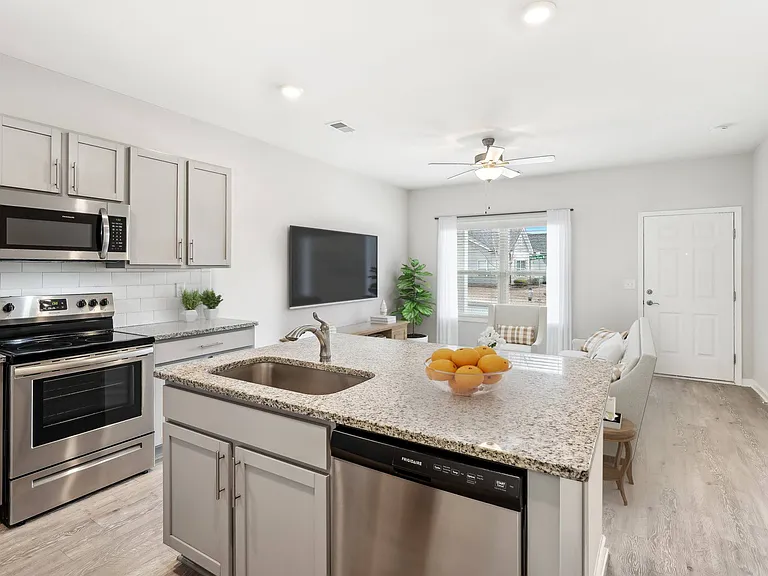 Spacious kitchen with an island, ample storage, stainless steel appliances and view into the living room.
