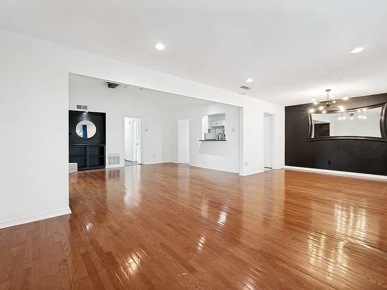 Bright interior with rich wood-finish flooring, recessed lighting, and a textured accent wall