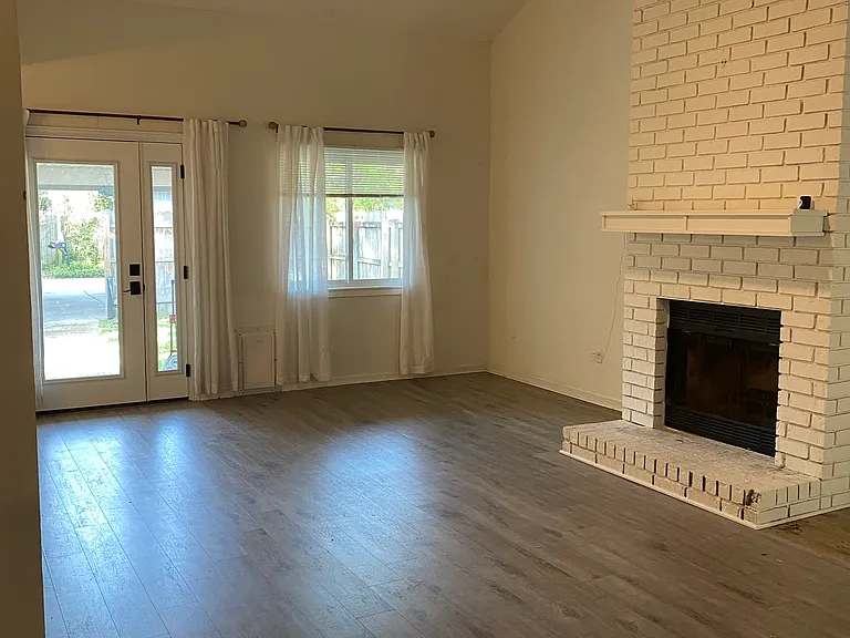 Living room _ vaulted ceiling, remote controlled ceiling fan & light, fireplace, curtains and blinds (view of back door)