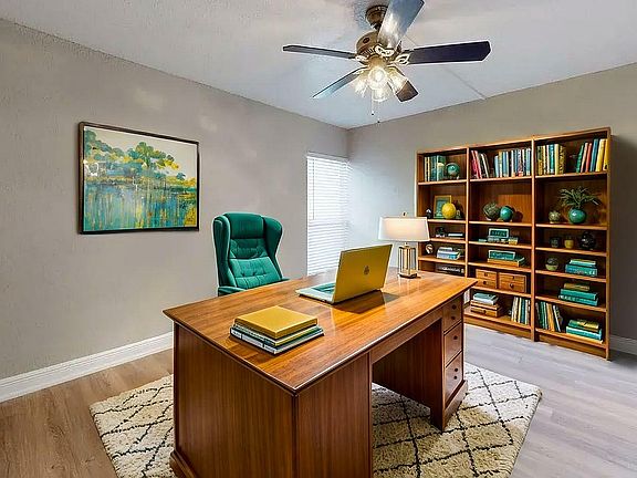 Elegant home office with a spacious wooden desk, plush green chair, and a cozy rug. Natural light enhances the inviting atmosphere, complemented by a well-organized bookshelf and modern decor.