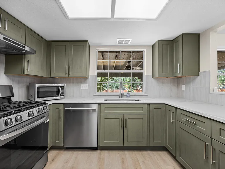 Newly renovated kitchen with gorgeous quartz countertops and sage green cabinets. The stove, dishwasher, and fixtures are all new and premium quality.
