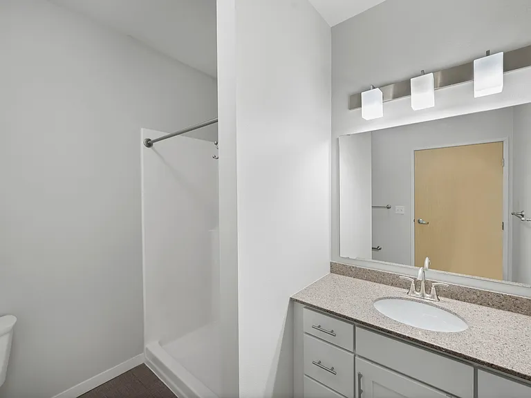Modern bathroom featuring sleek lighting, elegant countertop, and a spacious shower area against a bright background. Modern bathroom featuring sleek lighting, elegant countertop, and a spacious shower area against a bright background.