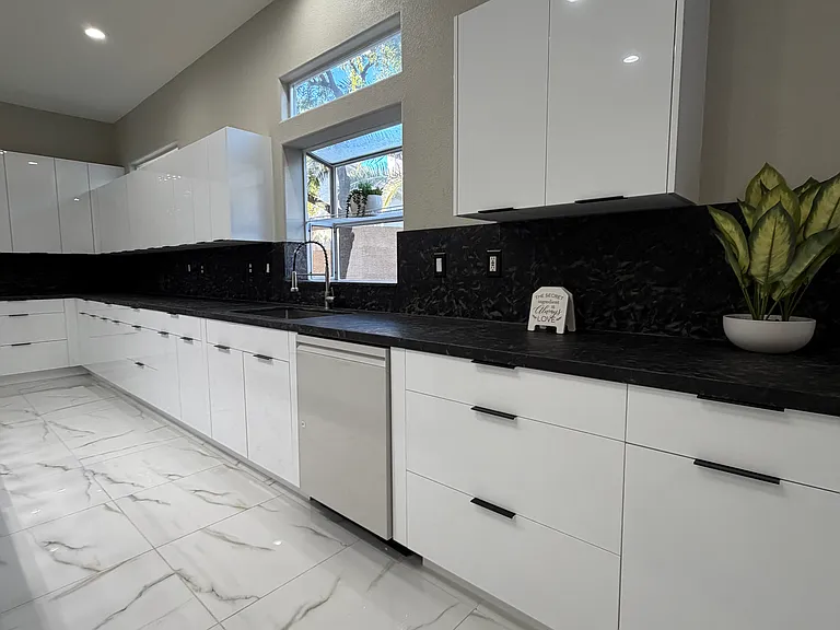 Alternate view of the contemporary kitchen featuring premium LG white-glass appliances and expensive granite countertops.
