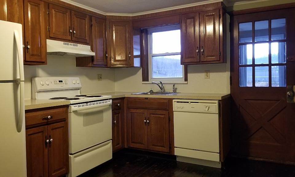 Kitchen with full size refrigerator, stove, and dishwasher. Front door on the right.