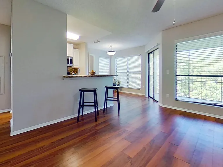 The Martinique Autograph floor plan features a spacious, open-concept living area with warm wood-style flooring, large windows, and a breakfast bar, perfect for entertaining or enjoying quiet moments at home.