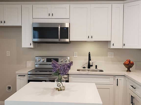 Shaker style cabinets with quartz countertop and all stainless microwave and stove