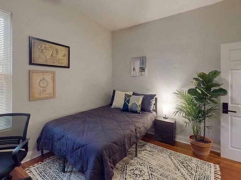 Well-appointed bedroom with a comfortable bed, nightstand, and a window with blinds for natural light and privacy.