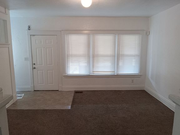 Looking back into living room from dining room showing picture windows at front entry door