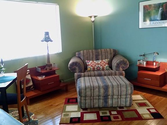 Yummy oversized Lazy Boy chair adjacent to small dinette area viewing courtyard and real wood stove!