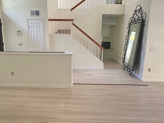 Two story entry way, with sky-lighted stairwell. Partial view of bright, spacious, living room with two story ceiling. Blonde oak hardwood floors and plenty of windows throughout.