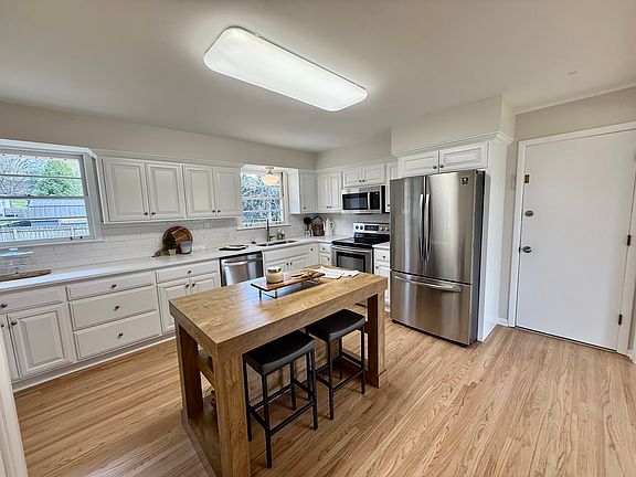 Another view of the large kitchen. new light fixture over the sink, tiled backsplash, lovely quartz countertops and new hardwood floors...