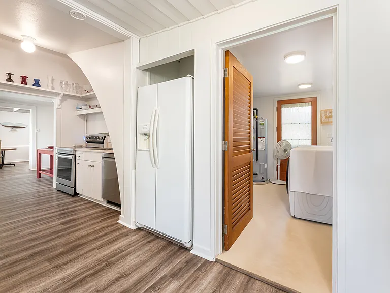 Functional kitchen and laundry area featuring full-size appliances, ample storage, and direct access to the backyard and outdoor spaces.
