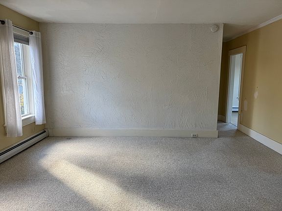 Living room with hallway to home office/bedroom on left and kitchen on right.