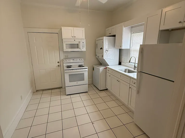 Kitchen with electric stove, microvawe, washer/dryer (in the corner), new cabinets, sink, faucet and quartz counter top and refrigerator with a freezer.