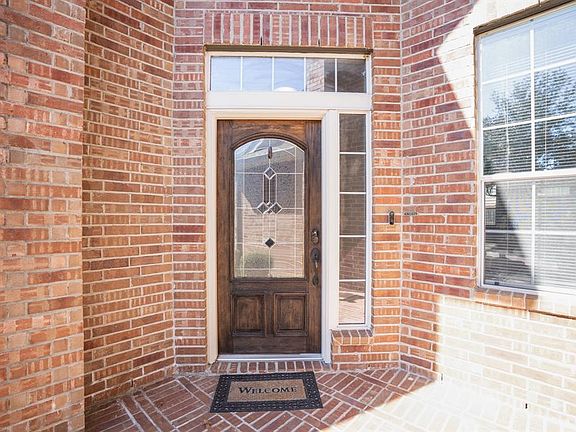 The high covered porch creates a grand entrance to the home where a timeless dark wood stained door w/ detailed glass panes offers a welcoming sight. The sidelight window to the side of the door are fogged for added privacy.