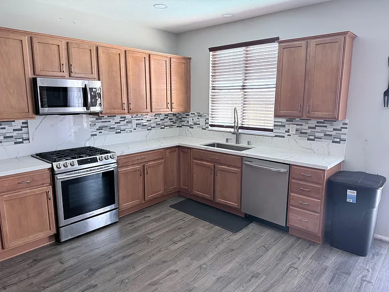 Updated kitchen with ample cabinetry, stainless steel appliances, quartz-style counters, and a large window over the sink.