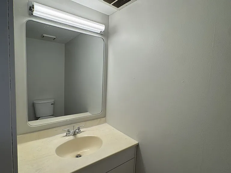 Fully renovated powder room with a stylish mirror and ribbed light bar (1/2).
