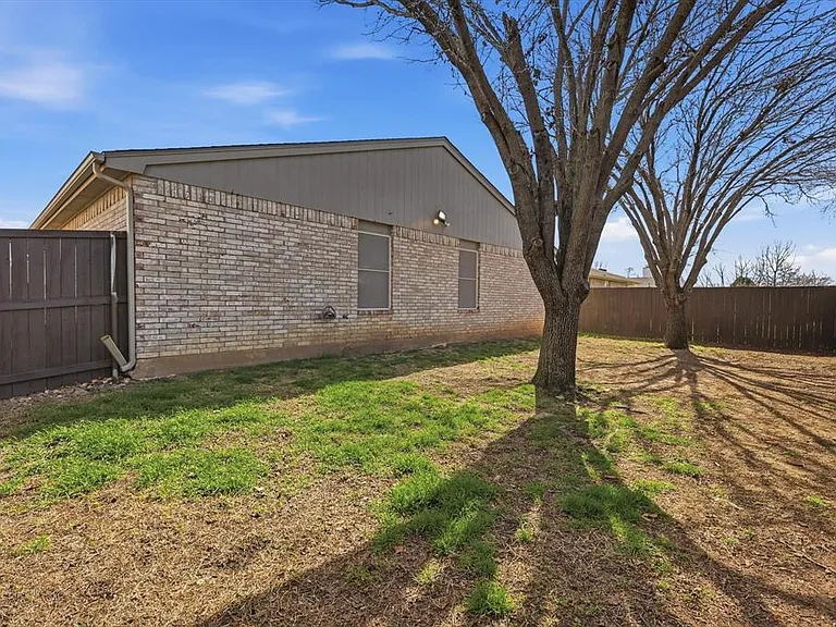 View of property exterior with a fenced backyard and brick siding