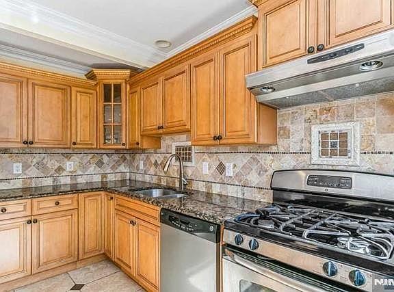 Glorious modern eat in kitchen with warm toned wood cabinetry and SS appliances.