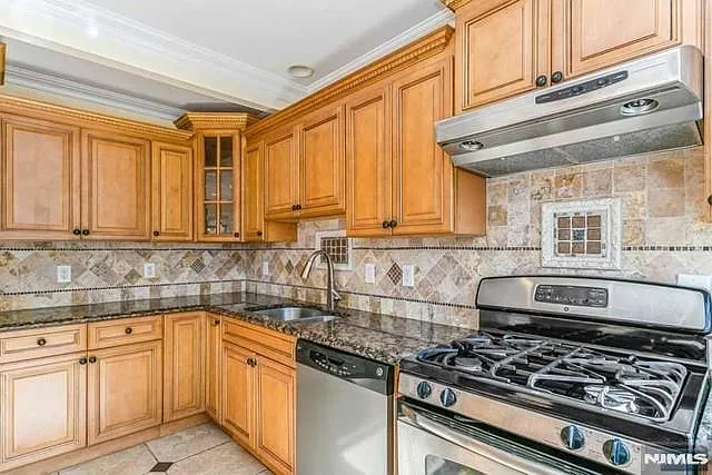 Glorious modern eat in kitchen with warm toned wood cabinetry and SS appliances.