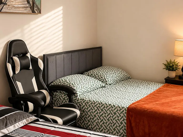 Bedroom with two beds, a nightstand lamp, and a desk chair, offering comfortable sleeping space and flexible setup.