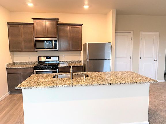 Open kitchen equipped with a full suite of Whirlpool appliances, granite countertops and plank flooring!